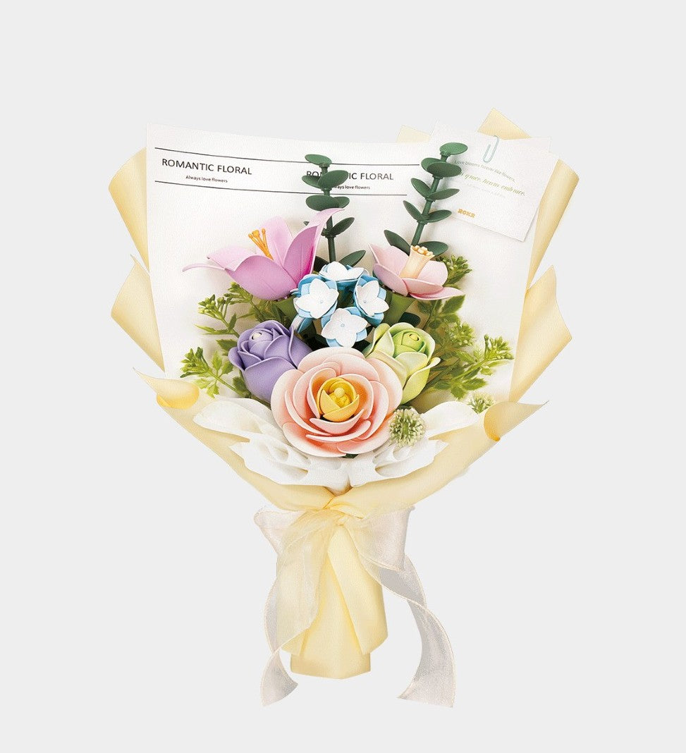 Bouquet of colorful artificial flowers wrapped in yellow paper on a white background