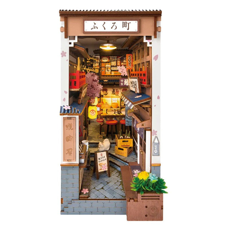 Model of a small town street with shops and signs on a white background