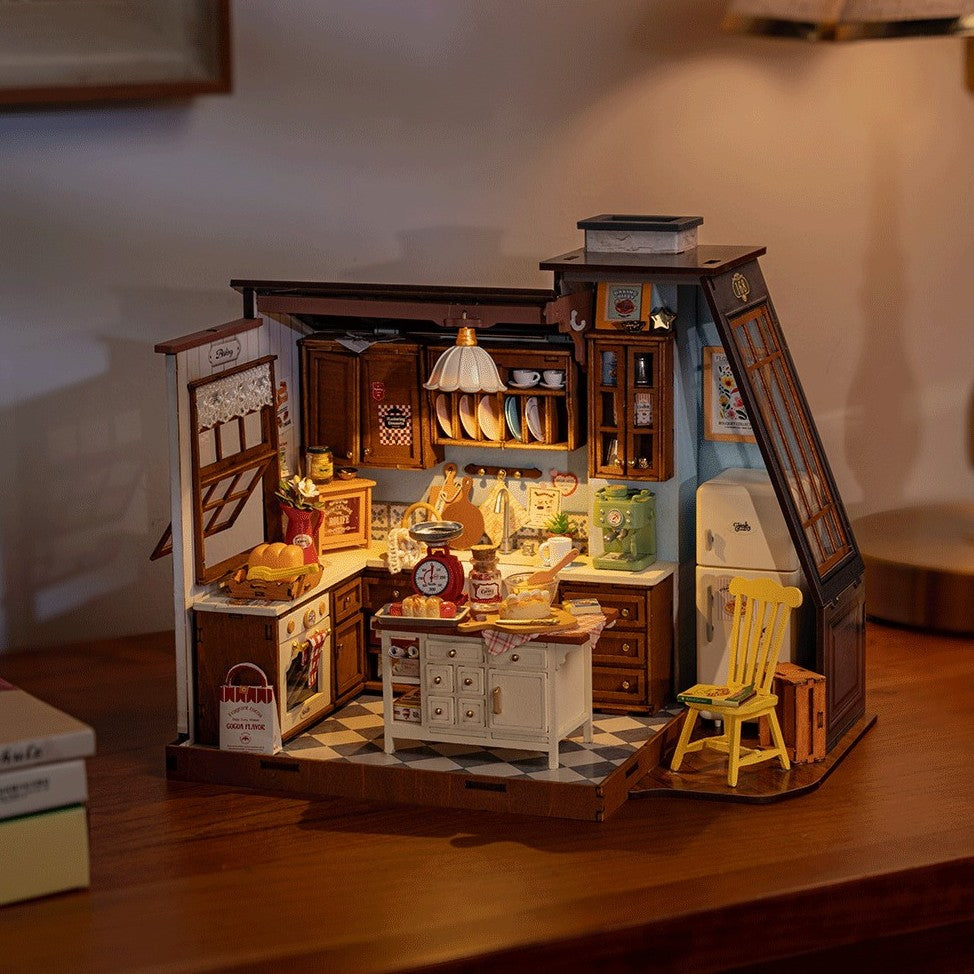 Detailed model of a miniature kitchen with various appliances and furniture on a wooden surface.