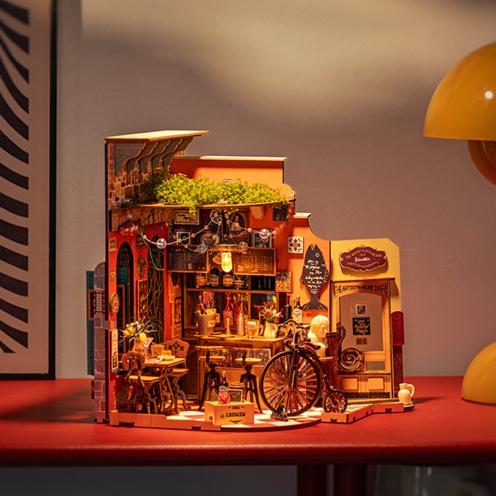 Detailed model of a miniature restaurant on a red surface with a warm light.