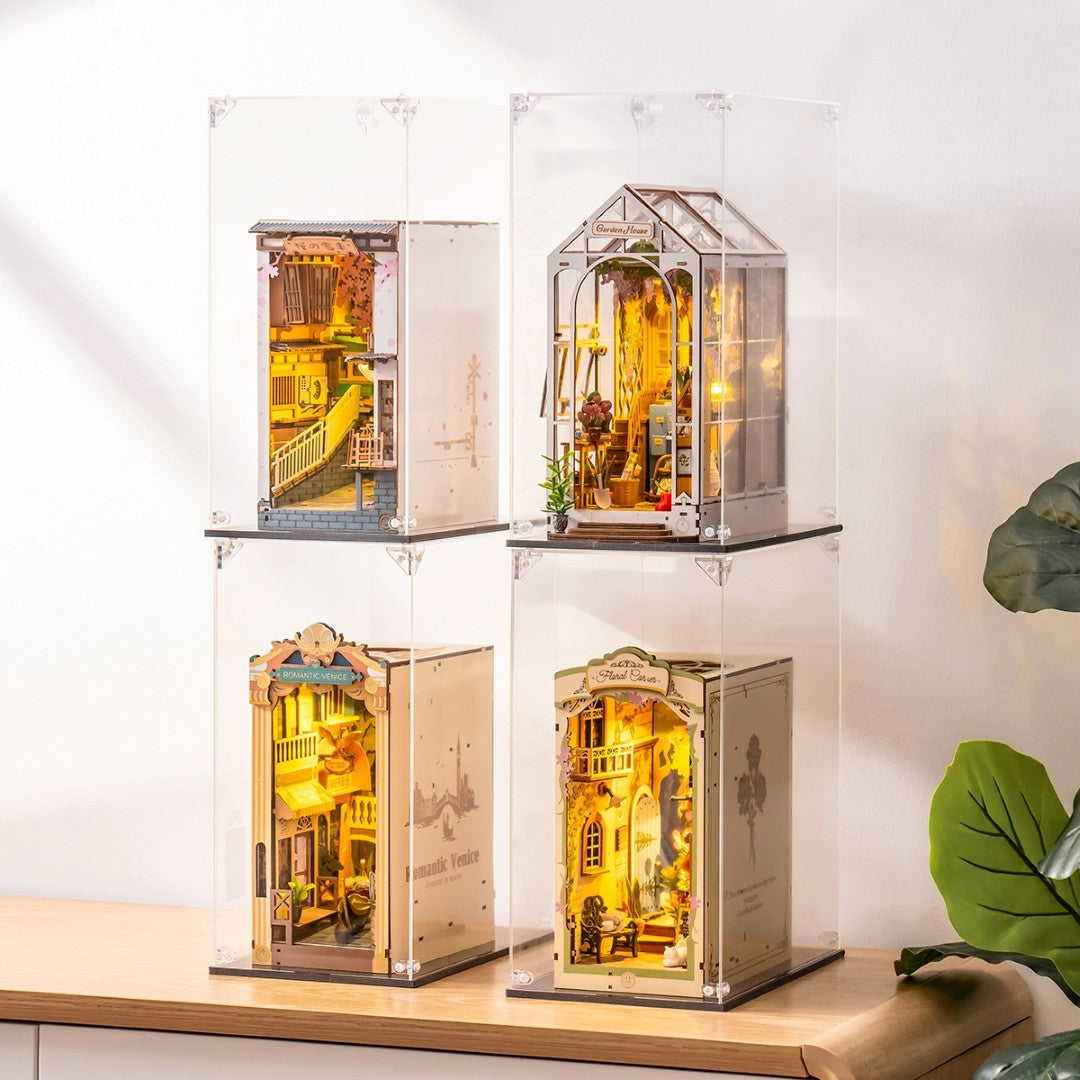 Four book nooks in display cases on a wooden surface.