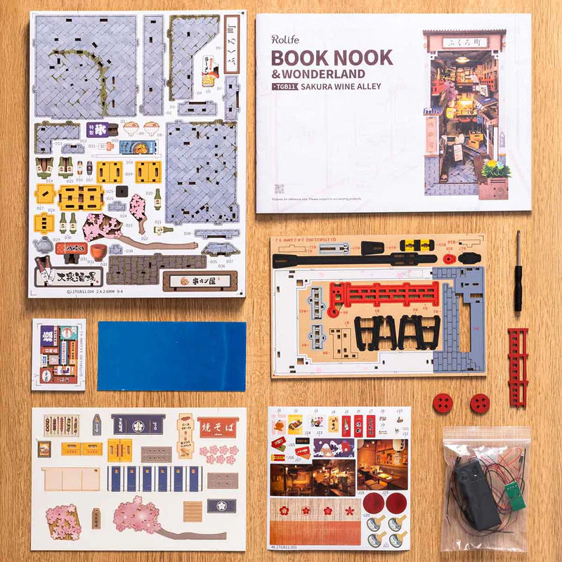 Model building kit with various components and a book titled 'Book Nook & Wonderland' on a wooden surface.
