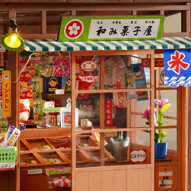 A miniature dollhouse-scale model of a Japanese street food stall named 'Hakuiyabaru', featuring a green and white striped awning, wooden interior shelves filled with toy products, and decorative signs.