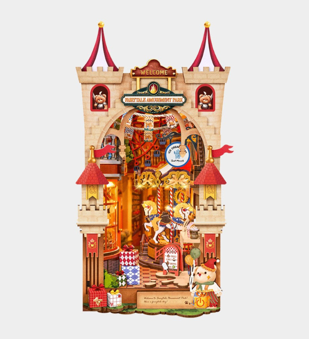 A detailed, multi-layered cardboard cutout model of a fairytale castle, featuring a carousel, a knight in armor, a dog character, and red-roofed towers, shown against a solid light gray background.